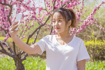 Smiling young woman taking a selfie with spring flower