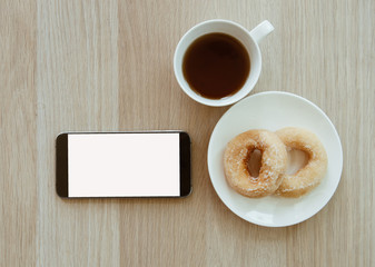 smart phone and tea and donut on wood table