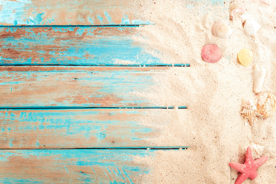 Beach background - top view of beach sand with shells, starfish on wood plank in blue sea paint color background. summer vacation concept. vintage color tone.