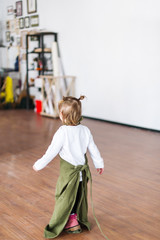 Cute blonde little girl in white jacket and green apron is in a creative class.