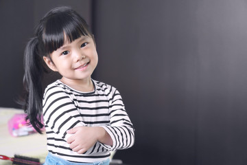 Asian children cute or kid girl feel business child with cross one's arm and smile white teeth with confidence after dressed up in the room at home office on black with space