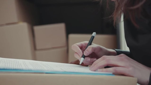 Close up hands courier African American gives a parce to a woman after signing on delivery device cardboard technology box order post postal service device sunny beard covered load logistic mailman
