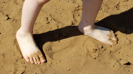 A small child walks on the sand on the beach