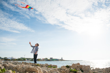 happy little boy with flying kite on sea town and sky background outdoors