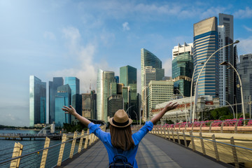 Young woman traveler with backpack and hat traveling into singapore city downtown. Travelling in Singapore concept - obrazy, fototapety, plakaty
