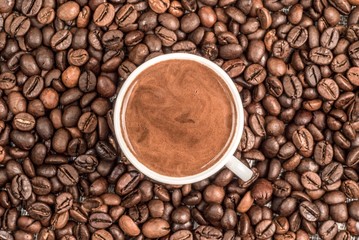 Fresh coffee surrounded by coffee beans