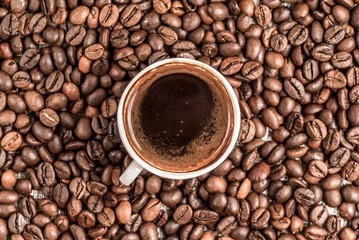 Fresh coffee surrounded by coffee beans