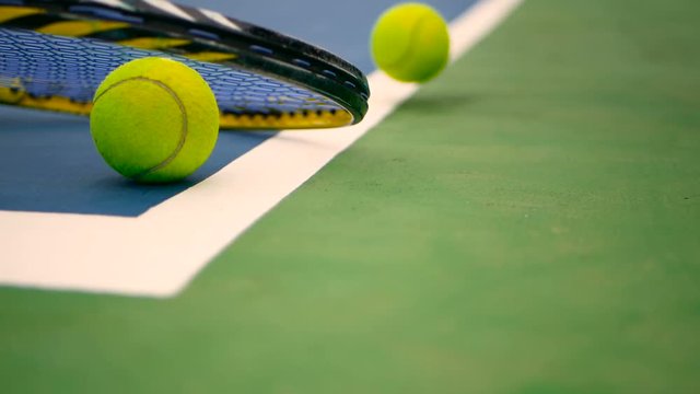 Close up of tennis equipment on the court. Sport, recreation concept. Yellow racket with a tennis ball in motion on a clay green blue court next to the white line with copy space and soft focus.