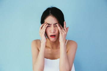 Young Asian woman having eye pain and soreness isolated over blue background - Healthcare and Medical concept