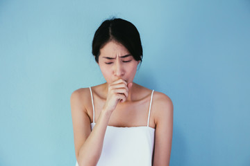 Young Asian woman suffering from cough / lung or throat problems isolated over blue background - Healthcare and Medical concept