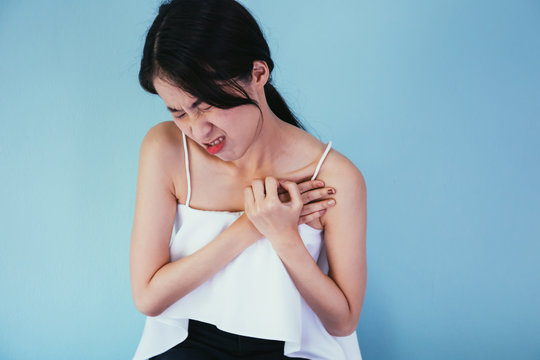 Young Asian Woman Having Heart Attack / Heart Burn Isolated Over Blue Background - Healthcare And Medical Concept