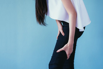 Young woman having leg pain / knee pain isolated over blue background - Healthcare and Medical...