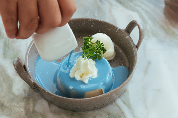 white pudding with vanilla ice cream and dripping sauce on stone table.