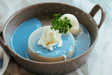 white pudding with vanilla ice cream and dripping sauce on stone table.