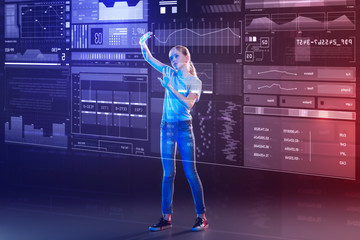 Creative schoolgirl. Calm attentive pupil feeling concentrated while standing in front of a large transparent device and learning how to use it