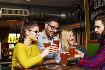 Fototapeta premium Group of four friends drinking beer and chat on lokal cafe