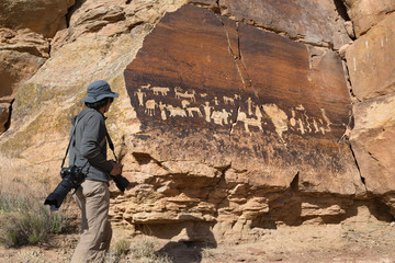 Male photographer standing in front of Native American Petroglyphs, Canaan Gap, Utah