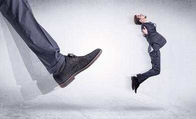 Boss mobbing his worker, illustrated by black shoe kicking small businessman who is flying away in...