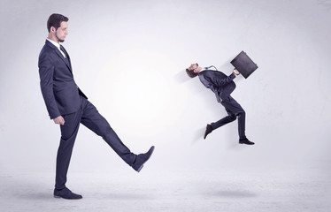 Big man in suit kicking out little himself out with simple white wallpaper
