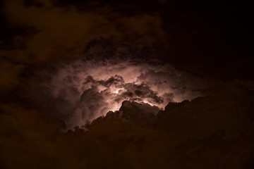 Lightning in the night sky is high in the mountains. Flashes of electrical discharges among the clouds and deafening thunder.