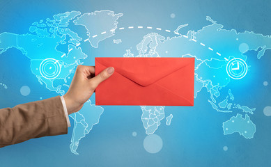 Female hand holding coloured and white envelope with blue map on the background
