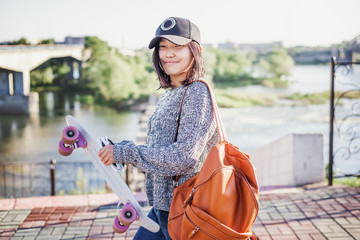 cute attractive stylish asian girl teenager 15-16 years old on city streets with skateboard in hands, millenial, youth lifestyle © olezzo