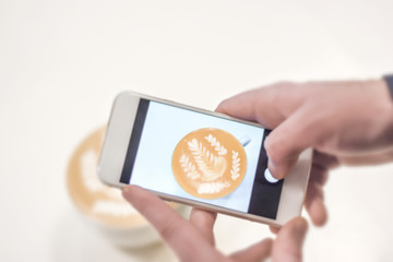 Mobile fotograph shoot of cafe latte on white table