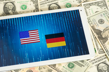 Dollar Geldscheine, Tablet PC und Flaggen von USA und Deutschland