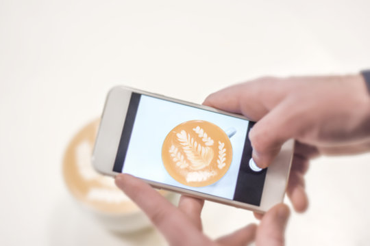 Mobile fotograph shoot of cafe latte on white table