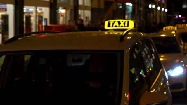 : Hand held panning night time video of taxis and people in Rosenthaler Strasse, Berlin, Germany
