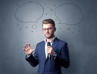 Businessman speaking into microphone with speech bubbles over his head