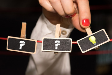 Eine Frau, Fragezeichen und eine Glühbirne als Symbol für eine Idee