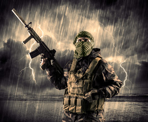 Portrait of a dangerous armed terrorist with mask and gun in a thunderstorm with lightning