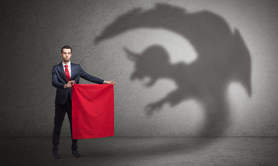 Businessman standing with red cloth in his hand and imp shadow on the background
