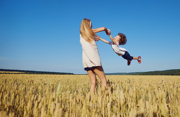 Mother turns a child having fun on the nature in the summer. Mothers Day.