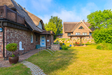 Fototapeta na wymiar SEEDORF VILLAGE, RUEGEN ISLAND - MAY 27, 2018: Garden with traditional thatched roof houses near Seedorf village, Baltic Sea, Germany. Rugen is popular tourist destination due to its rural landscape.