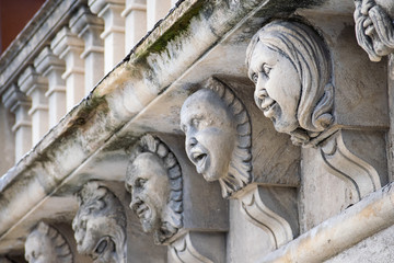 Closeup view of mascarons with funny faces under the balcony of a baroque palace in the province of Syracuse, Sicily