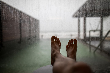 feet on table when seeing raining outside window