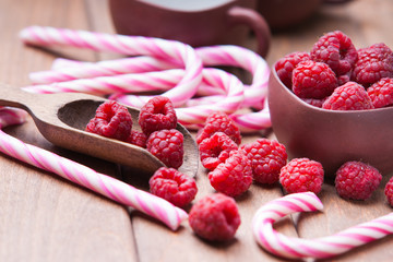 Raspberries in a cup, candy canes and wooden scoop 