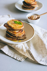 Banana pancakes with walnuts and cedar nuts, honey and mint, honey dipper on a white background. Morning breakfast
