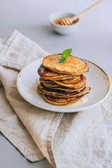 Banana pancakes with walnuts and cedar nuts, honey and mint, honey dipper on a white background. Morning breakfast