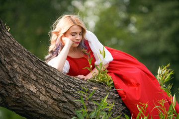 girl elf on a tree branch, in a red dress and a white blouse. resting bored