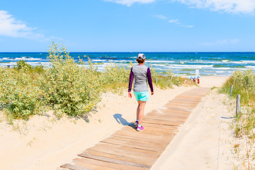 Young woman tourist walking to beach with sand dunes in Baabe village, Ruegen island, Baltic Sea, Germany