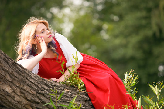 girl elf on a tree branch, in a red dress and a white blouse. resting bored