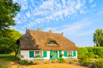 Fototapeta na wymiar Typical house with straw roof in warm sunset light and sunny blue sky near Ostseebad Sellin, Ruegen island, Baltic Sea, Germany