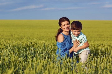 Fototapeta premium Mother and son play fun in the field of wheat in nature.