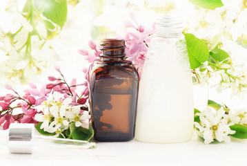 Aromatic botanical natural beauty treatment products. Cosmetic bottles with essential oil and skincare cleansing foam with flower blossom, soft light.