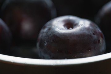 closeup of freshly washed big plums in a steel bowl
