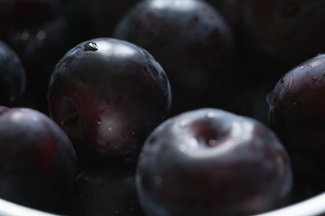 closeup of freshly washed big plums in a steel bowl