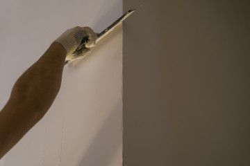 worker applying putty on the wall with putty knife